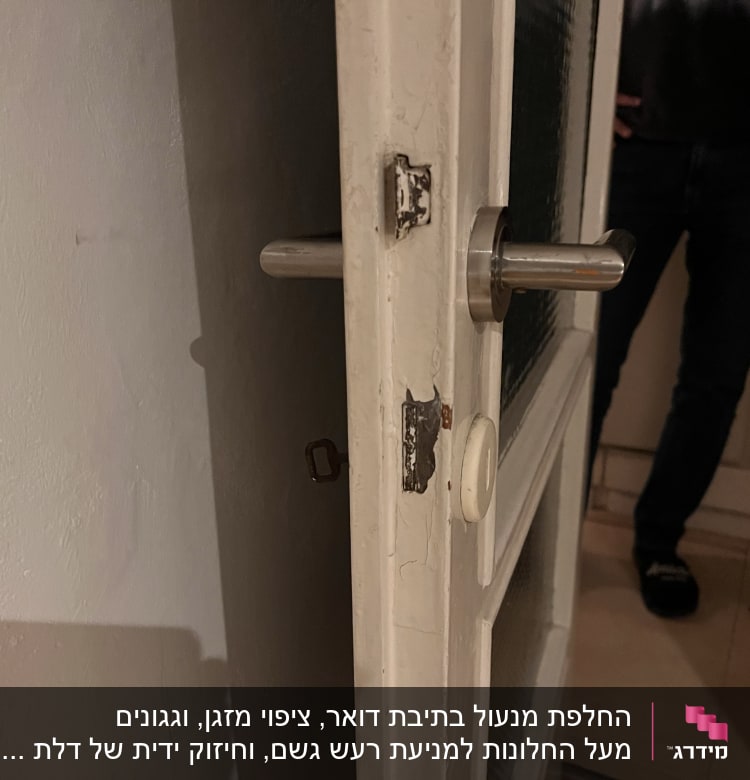 ידית דלת מתכתית על דלת עץ ישנה